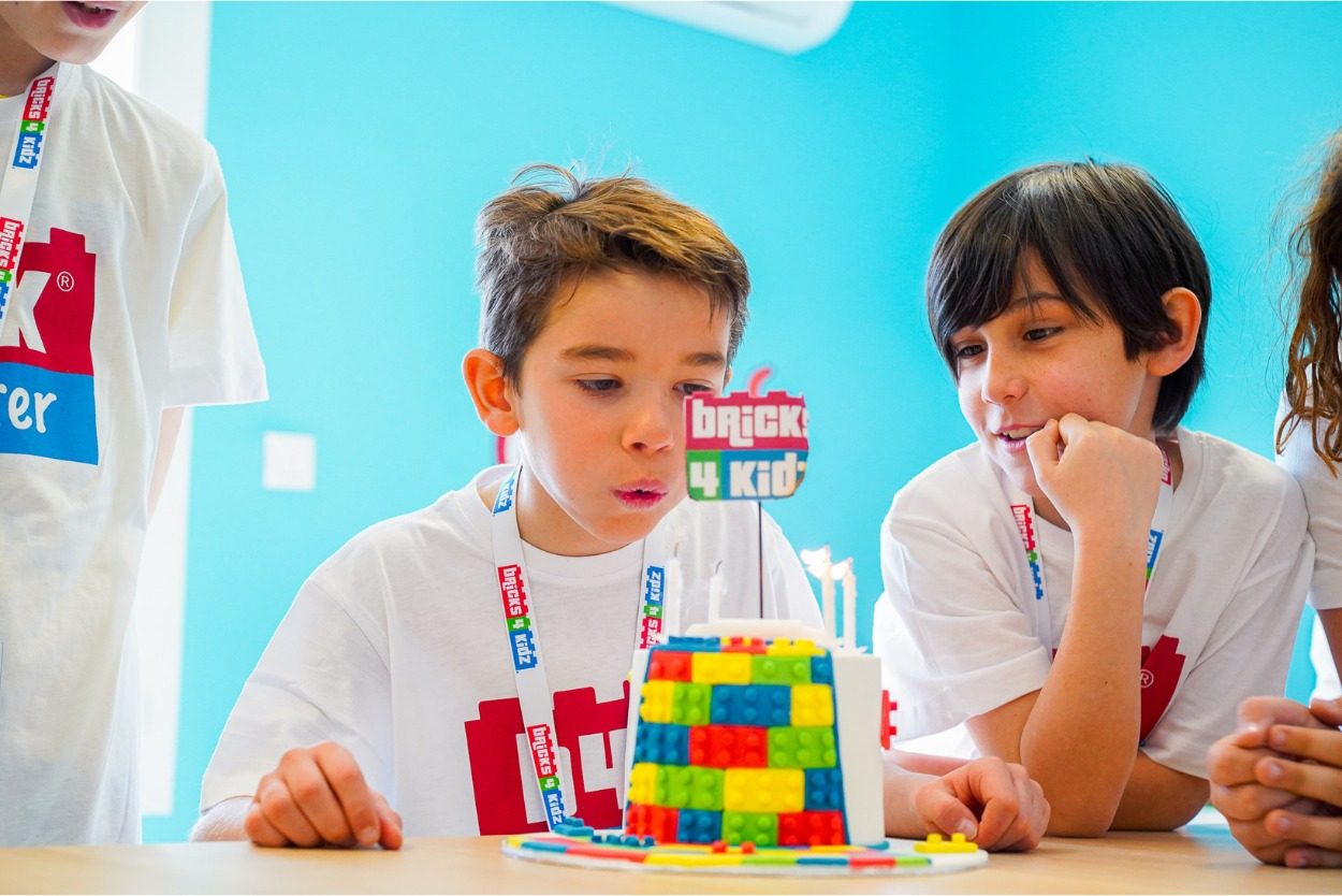 Zwei Kinder in Bricks 4 Kidz T-Shirts, konzentriert bei ihrer Konstruktion